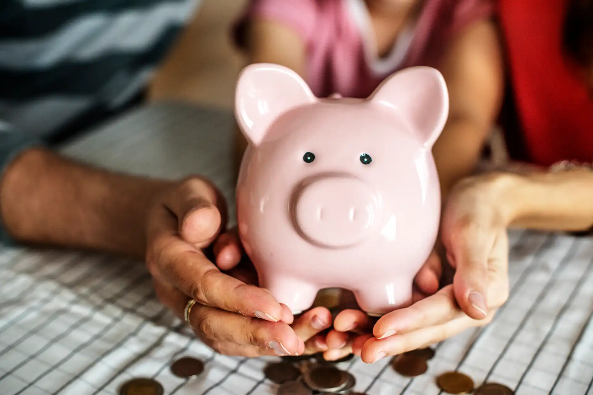 Pessoa segurando uma piggy bank rosa, simbolizando economia e finanças, com moedas ao redor, explicando o conceito de royalties na economia e direito.